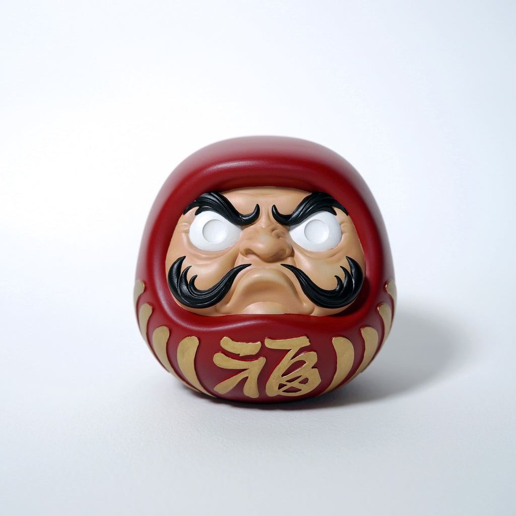 Front view of red Japanese Daruma doll with gold kanji and smooth resin finish