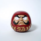 Front view of red Japanese Daruma doll with gold kanji and smooth resin finish