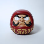 Close up front view of modern red Japanese Daruma doll with sculpted face