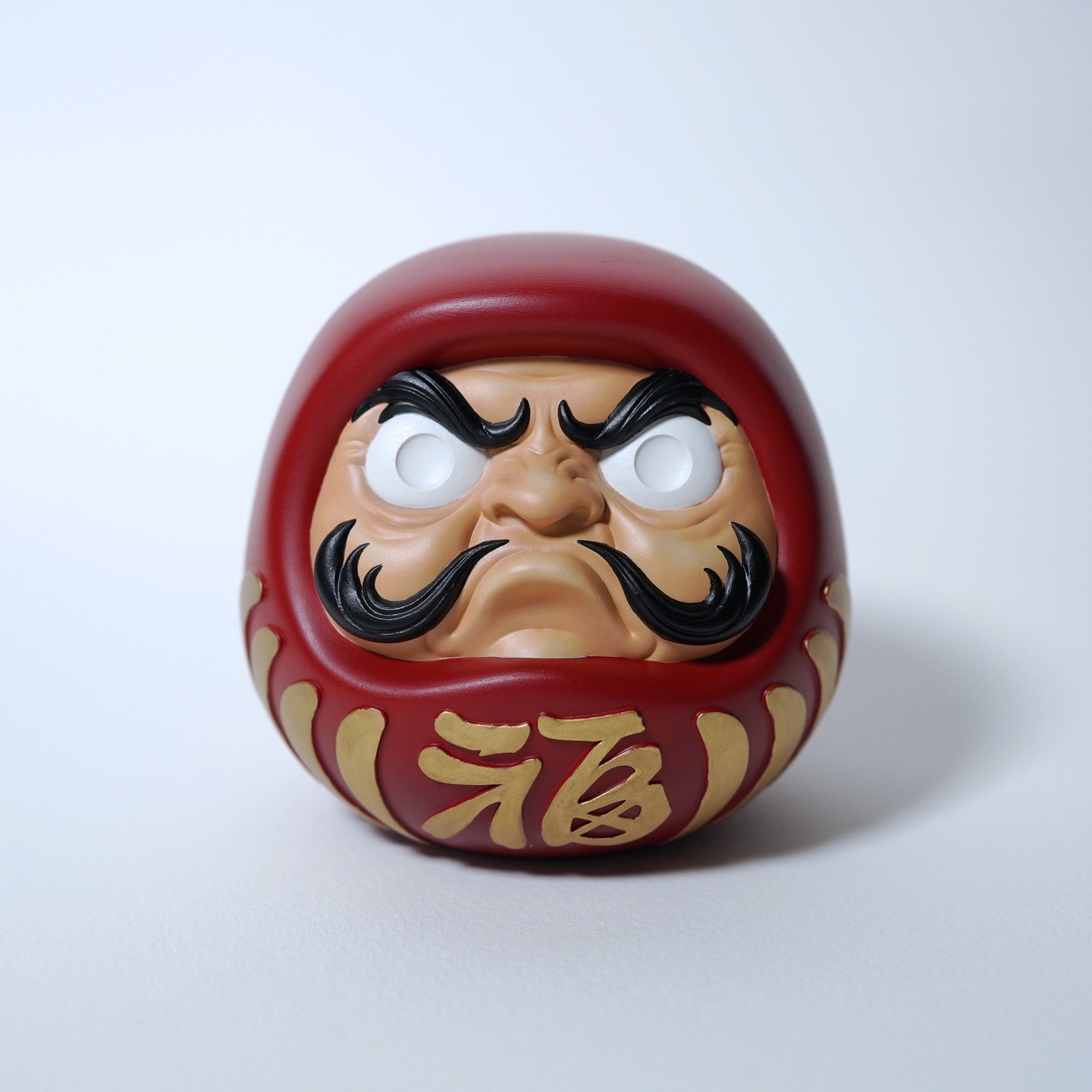 Close up front view of modern red Japanese Daruma doll with sculpted face