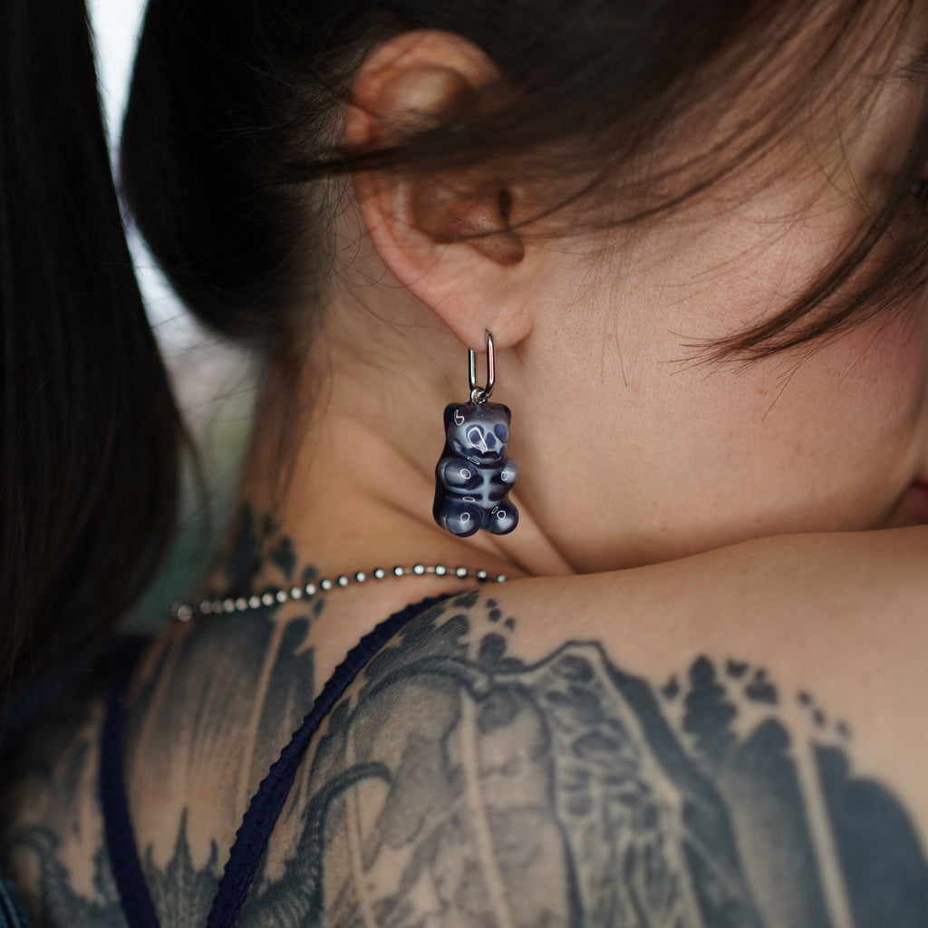 Close-up of transparent resin gummy bear skeleton earring, glossy handmade