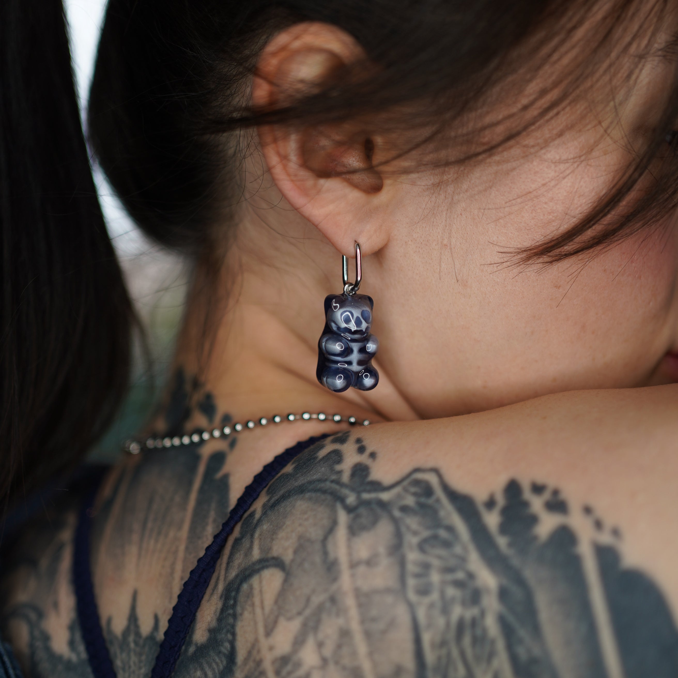 Close-up of transparent resin gummy bear skeleton earring, glossy handmade