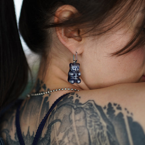 Close-up of transparent resin gummy bear skeleton earring, glossy handmade