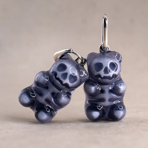 Pair of dark transparent gummy bear skeleton earrings in glossy resin, spooky cute handmade jewelry with visible skull details