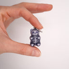 Close-up of transparent resin gummy bear skeleton earring, glossy handmade skull bear charm, dark aesthetic gothic candy jewelry