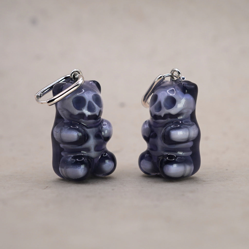 Mini transparent gummy bear skeleton earring shown in hand for scale, handmade resin skull bear charm, creepy cute gothic jewelry design