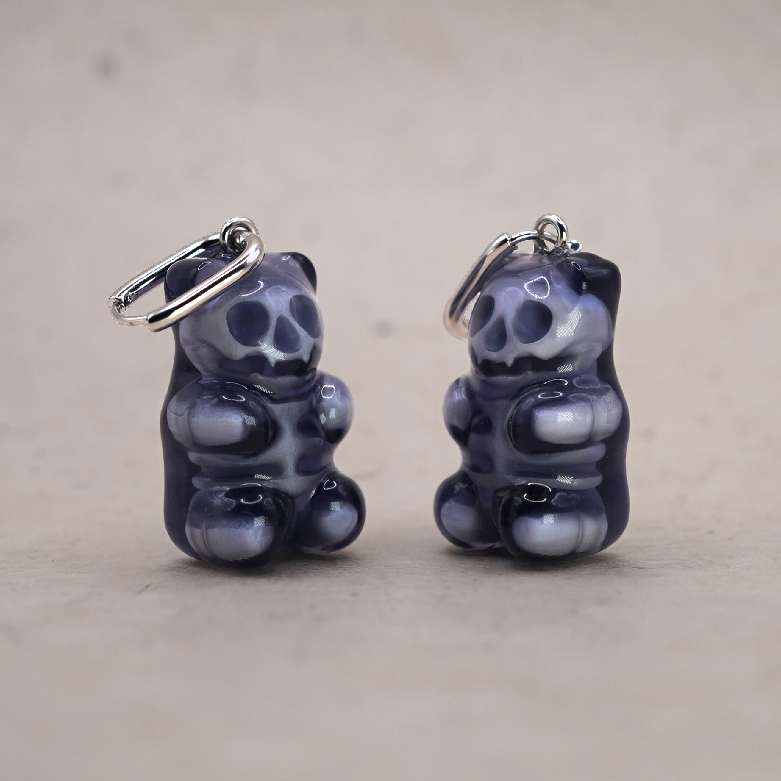 Mini transparent gummy bear skeleton earring shown in hand for scale, handmade resin skull bear charm, creepy cute gothic jewelry design