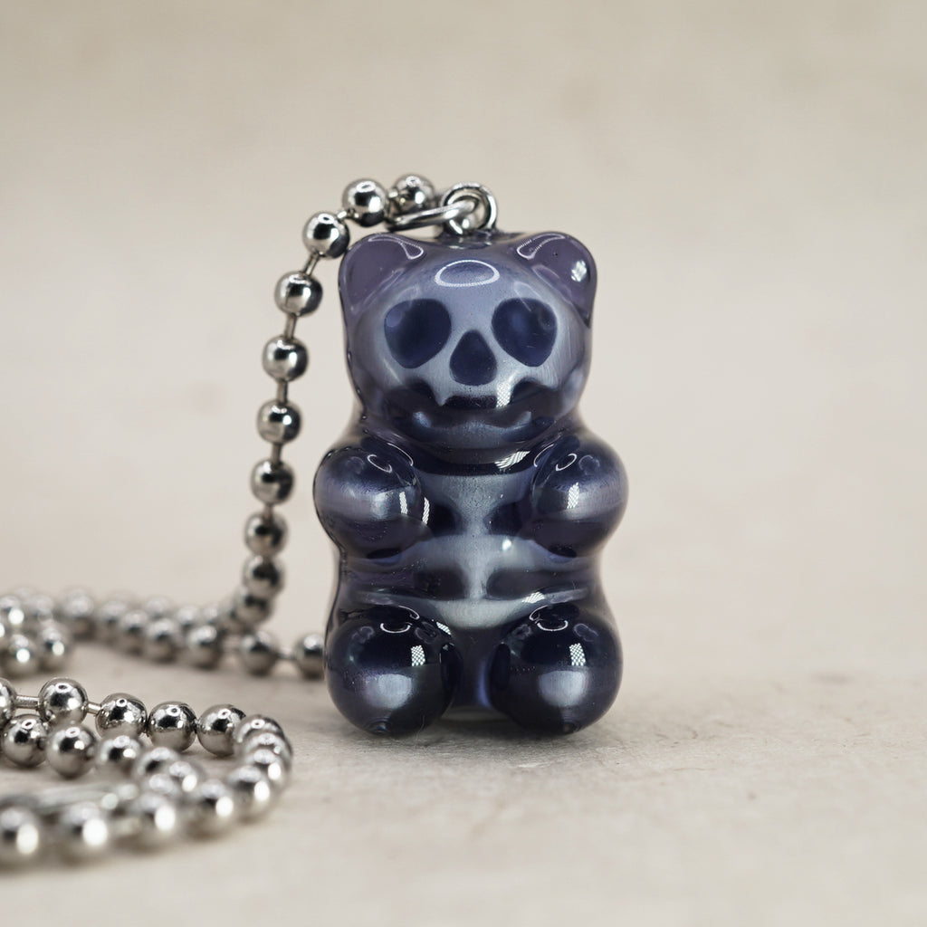 Black X-Ray gummy bear pendant with visible skull and ribcage, glossy resin charm on silver ball chain, front view close-up.