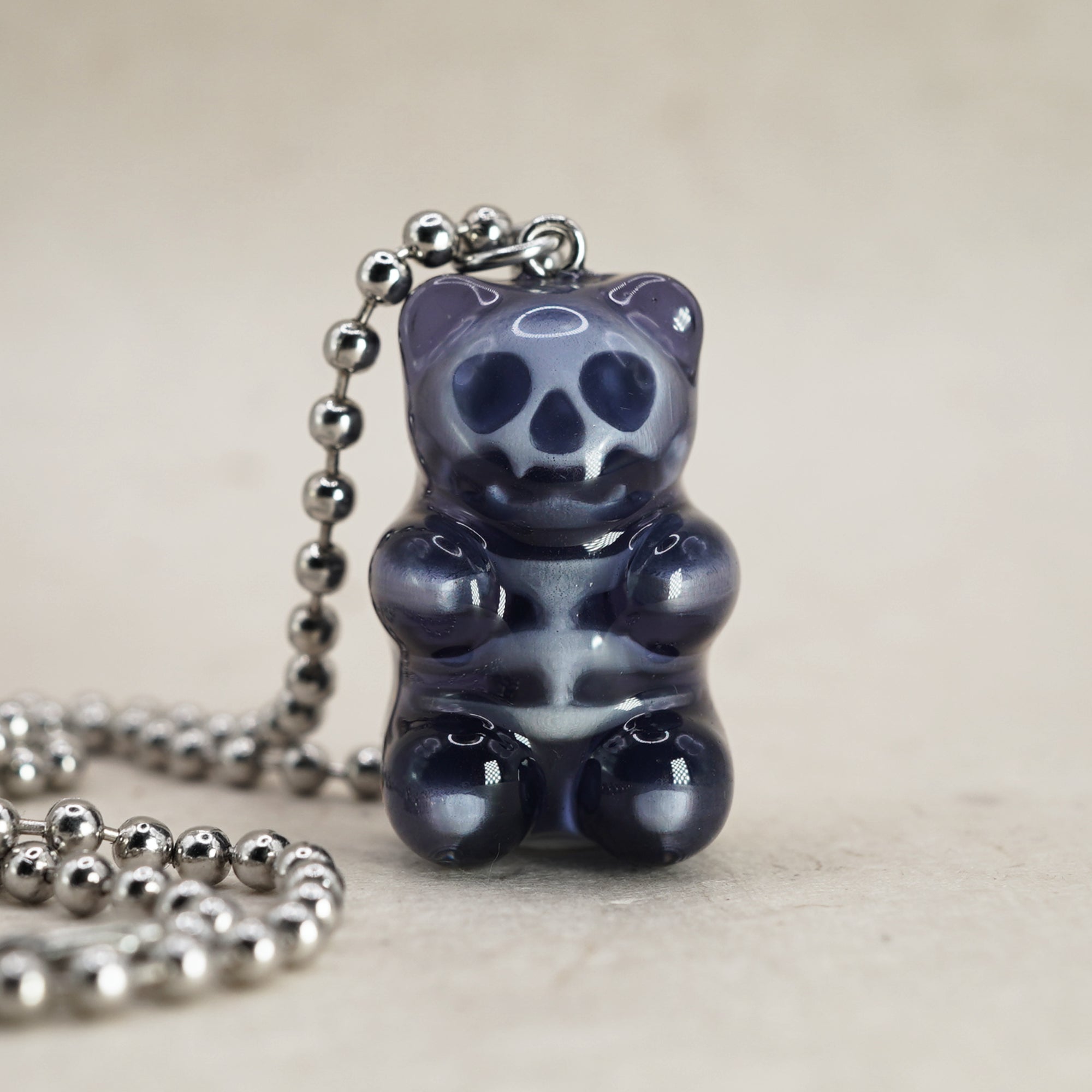 Black X-Ray gummy bear pendant with visible skull and ribcage, glossy resin charm on silver ball chain, front view close-up.