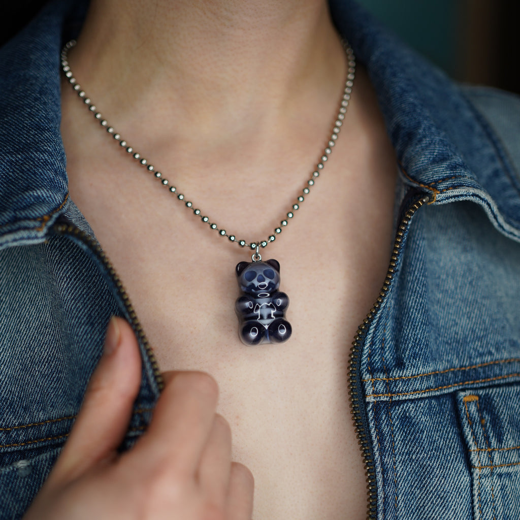 Worn shot of black gummy bear skeleton pendant on silver ball chain necklace, luxury alternative gothic candy statement charm.