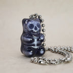 Side angle of black transparent gummy bear skeleton pendant on silver ball chain, glassy shine and spooky cute detail.