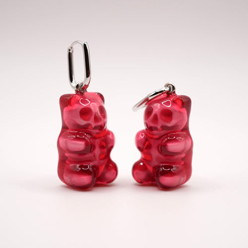 Pair of translucent red skeleton gummy bear earrings on a white background, 3D printed alternative wearable art.