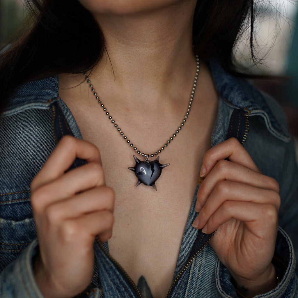 Model wearing spiked heart necklace, edgy chic broken heart pendant in black transparent resin on rhodium plated ball chain