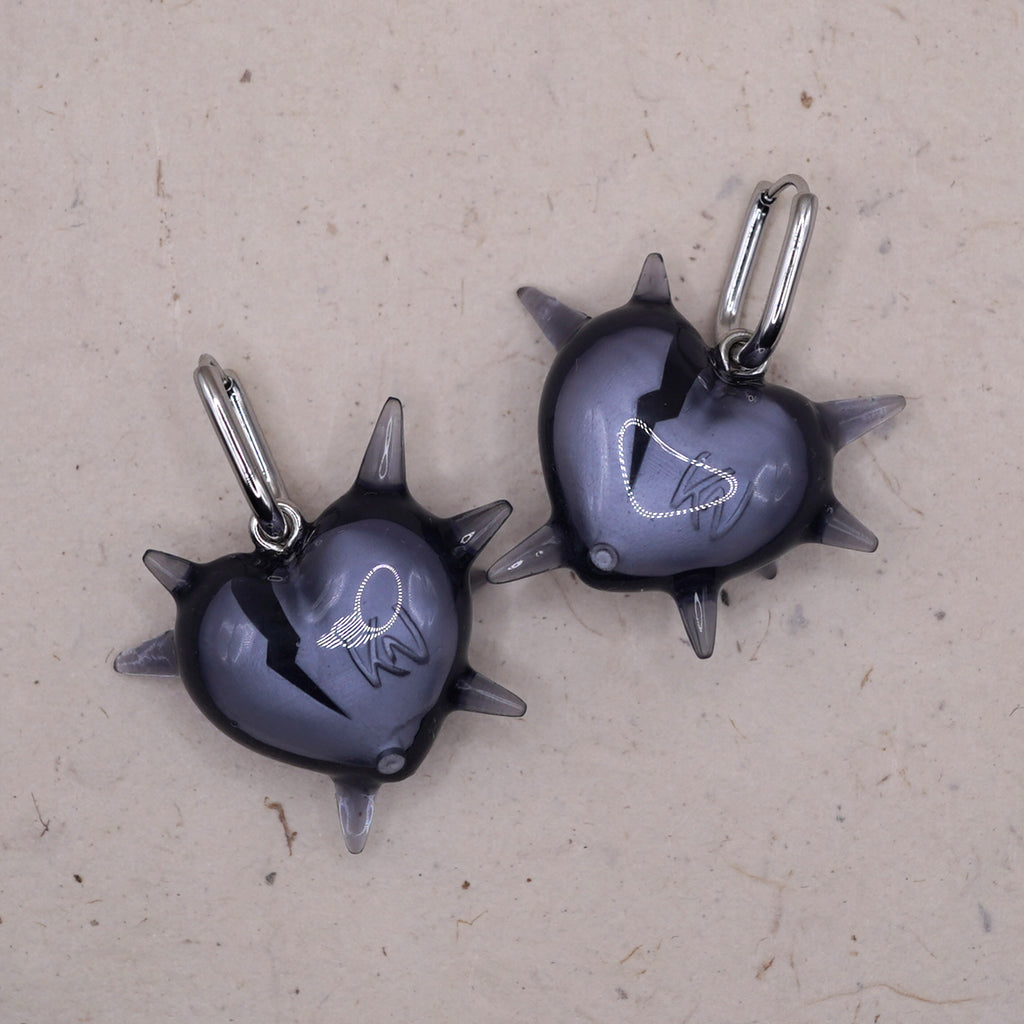 Close-up of spiked heart earring in transparent resin showing broken heart design, edgy gothic statement jewelry