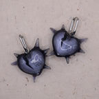 Close-up of spiked heart earring in transparent resin showing broken heart design, edgy gothic statement jewelry